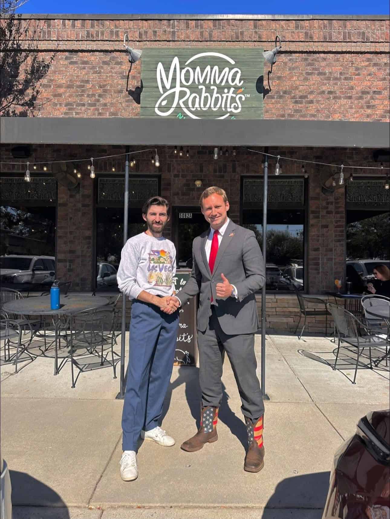 Entrepreneur shaking hands with a political figure outside a restaurant.