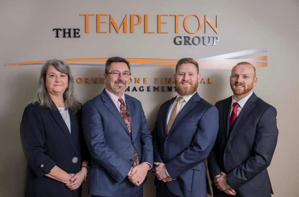 Four professionals in business attire pose in front of a wall sign that reads The Templeton Group.