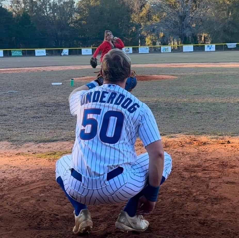 Young baseball player in pinstripe uniform crouching on the field during game.