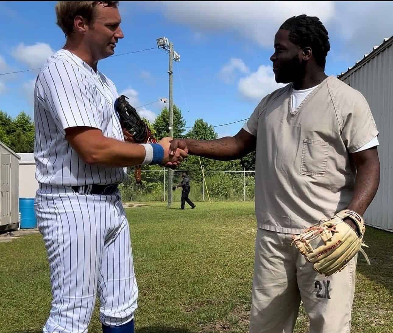 Baseball player shaking hands with a coach or fellow player after a game; sportsmanship and teamwork in baseball; outdoor sports field scene.