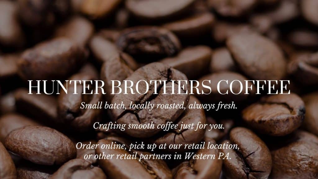 Close-up roasted coffee beans with white script text promoting Hunter Brothers Coffee (small batch, locally roasted).